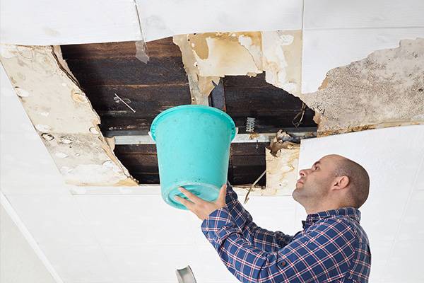 homeowner preventing roof leaks while waiting for a water damage public adjuster