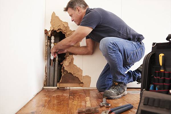 homeowner taking care of a pipe leak while waiting for a water damage claim filing